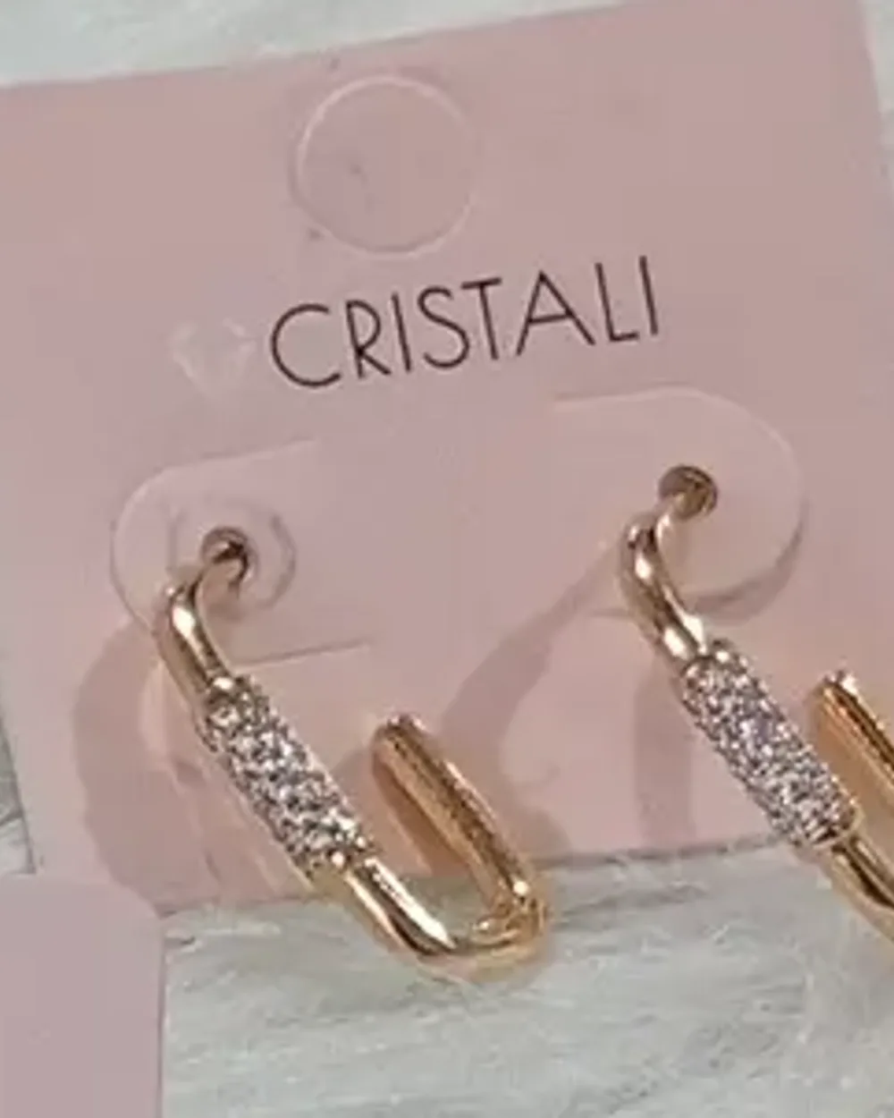 Brinco dourado em formato de gota alongada cravejada