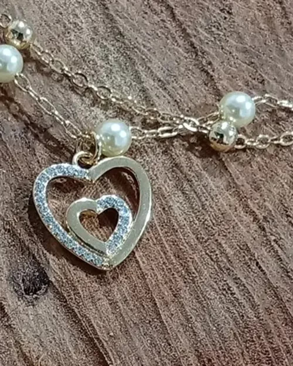 Pulseira dourada com pérolas e pingente de coração cravejado